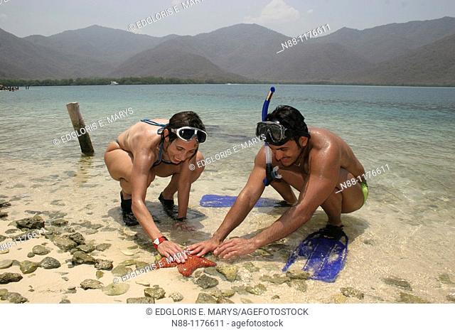 Snorkeling couple holding a starfish in the Caribbean, La Cienaga, Parque Nacional Henri Piitier, Venezuela