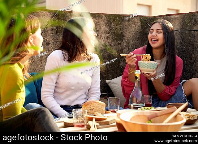 Cheerful female friends eating food on rooftop