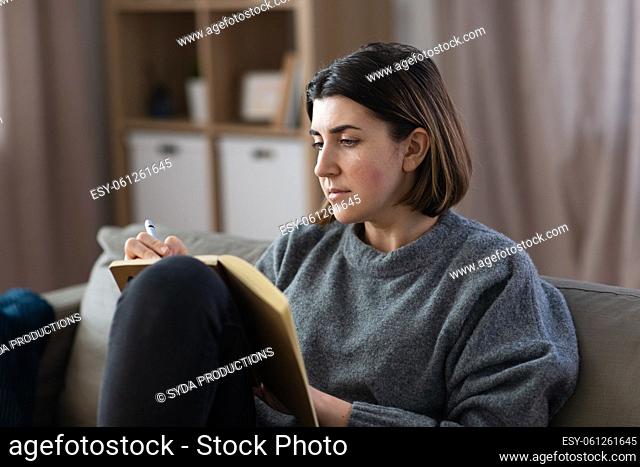 crying woman with diary sitting on sofa at home