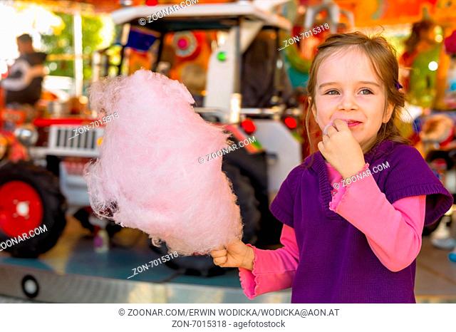 Ein kleines Mädchen auf einem Kirtag mit Zuckerwatte. Spaß und Freude am Jahrmarkt