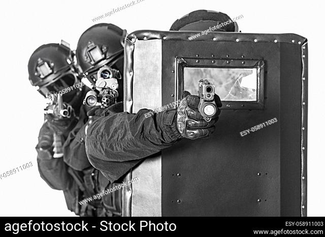 Studio shot of swat police special forces pointing criminals with rifle pistol hiding behind ballistic shield. Isolated on white