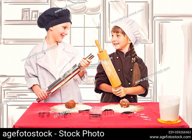 Beautiful boy and girl in chef clothes making christmas cookies with plunger. Children over kitchen drawing background