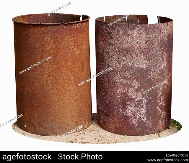 Rusty iron barrels stand on the ground near a village shed. Isolated