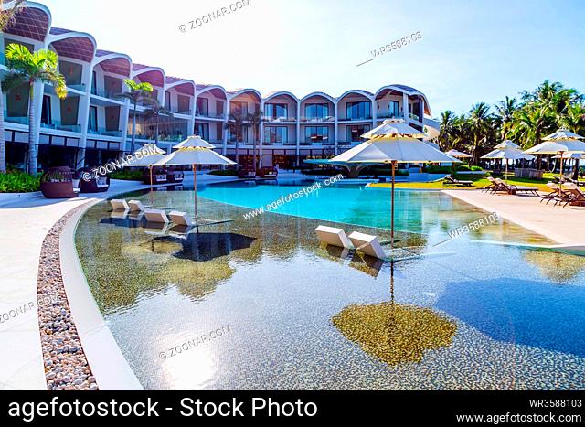 tropical resort hotel with swimming pool. Beach umbrella, beach chair tile floor marble ceramic mosaic. Vacation and travel concept