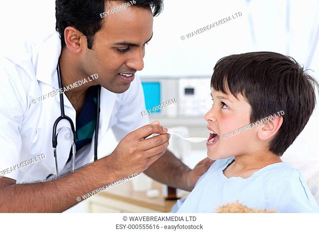 Young doctor giving medicine to a little boy at the hospital