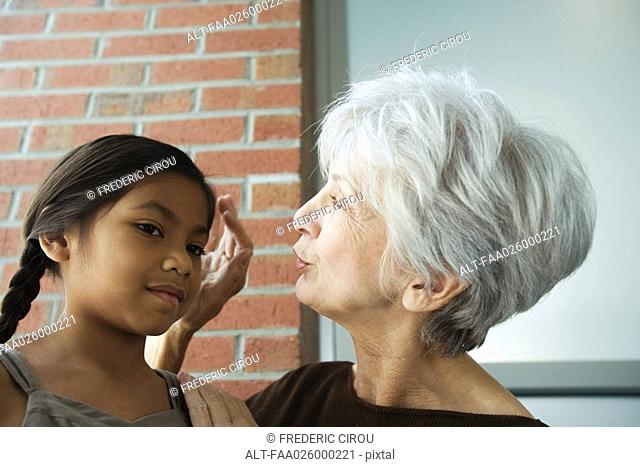 Grandmother touching granddaughter's head, close-up