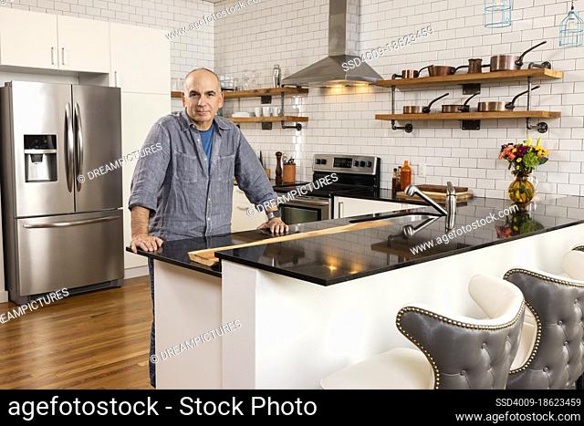 Portrait of a man standing in modern kitchen looking into camera