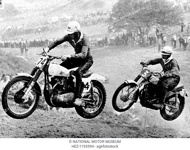 Two motorcyclists taking part in Motocross at Brands Hatch, Kent. They have been photgraphed in mid air. Spectators lining the course can be seen behind them