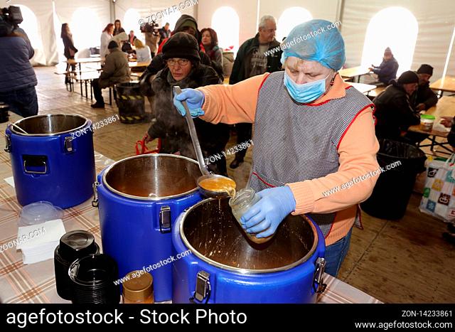Sofia, Bulgaria - 14 February 2019: ?mployee in a kitchen for poor and homeless people pours warm soups in containers for visitors of the kitchen