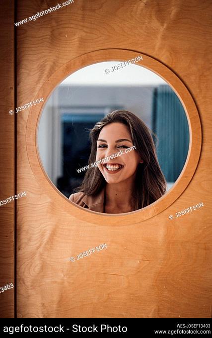 Cheerful businesswoman seen through glass