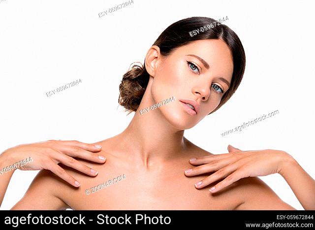 Beautiful young woman with natural makeup touching shoulder. Beauty shot. Isolated over white background. Copy space