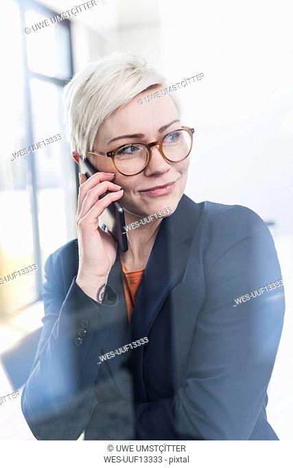 Portrait of confident businesswoman on cell phone in office
