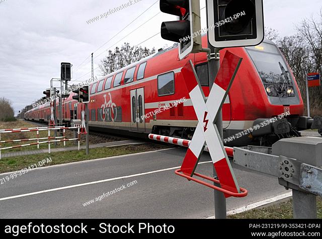 19 December 2023, Brandenburg, Vetschau/Ot Raddusch: The regional express train RE2 with destination Nauen coming from Cottbus passes a level crossing with...
