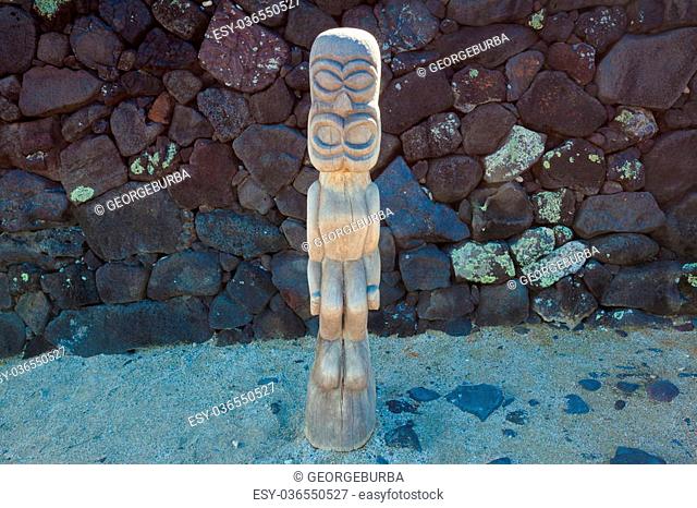 Old wooden protection idol with black lava stone background at an ancient Hawaiian site Pu’uhonua O Honaunau National Historical Park on Big Island, Hawaii