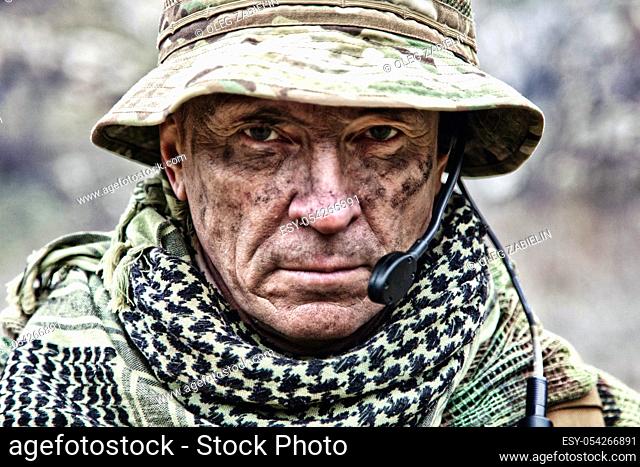 Close-up portrait of brutal commando veteran, experienced army commander or officer with dirty face, wearing camouflage bonnie, shemagh