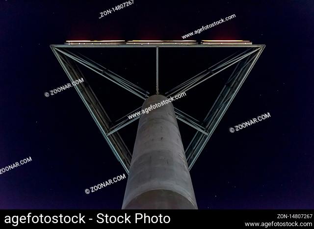 A concrete column with neon writing in a clear sky in the evening
