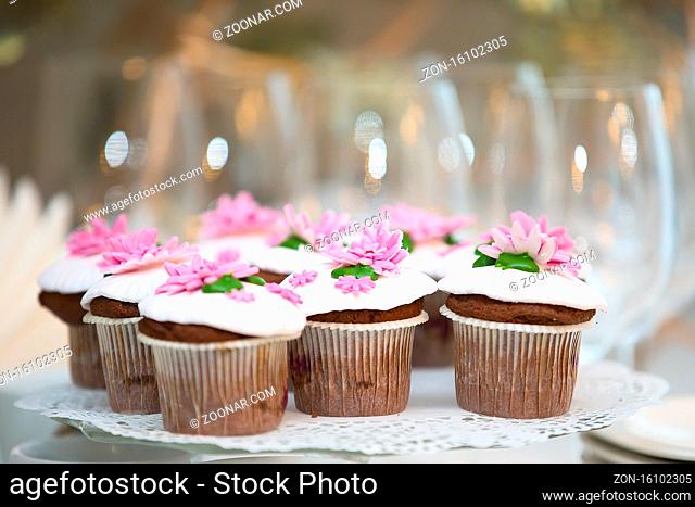 Cake for a buffet table. A group of small cupcakes decorated with pink cream flowers