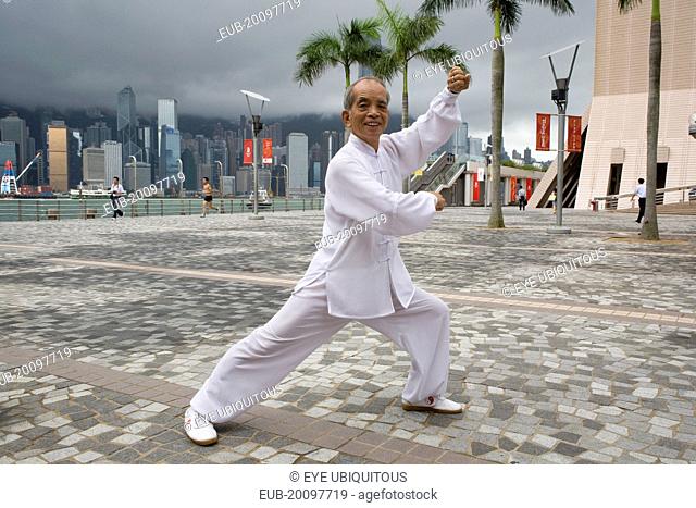 Tsim Sha Tsui Avenue of the Stars. Portrait of Tai Chi master Mr. Ng at a shadow boxing posture shoot at the Avenue of Stars with Hong Kongs skyscrapers...