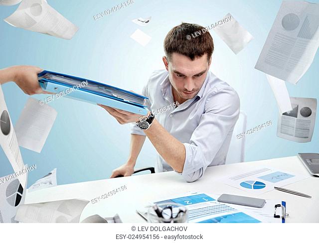 business, people, deadline and paperwork concept - businessman taking folder from secretary over blue background and falling papers