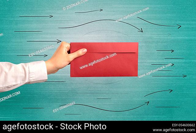 Female hand holding coloured and white envelope with green background and arrows around