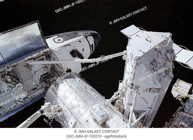 Backdropped by the blackness of space, the Space Shuttle Endeavour is pictured while docked to the Pressurized Mating Adapter (PMA-2) at the forward end of the...