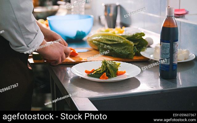 Male chef preparing salad in commercial kitchen, close-up