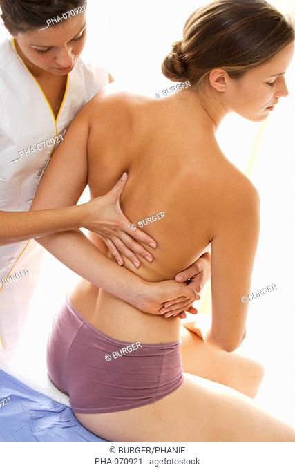 Back of a woman being manipulated by osteopath. Osteopathy uses massage and manipulation to treat a range of disorders, based on an understanding of the...