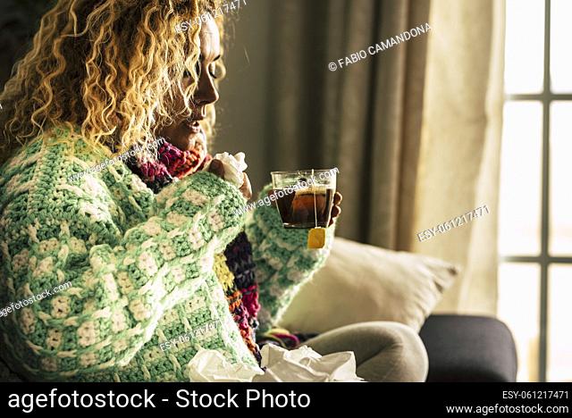 Coronavirus. SIck woman with cold flu influenza alone at home driniking herbal tea or medicine to fight the contagion - coronavirus lockdown covid-19 people -...