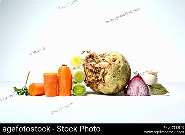 Still life of carrot, celeriac, red onion, leek, bay leaf, parsley, partly cut into pieces