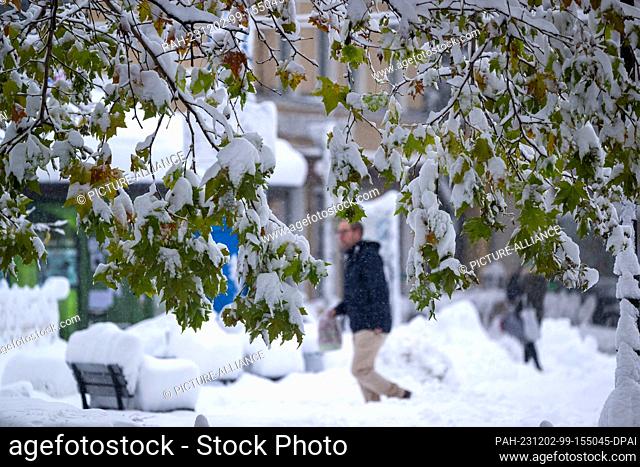 02 December 2023, Bavaria, Munich: A man walks through the snow-covered city. Snow and ice have caused chaos on the roads and on the railroads in southern...