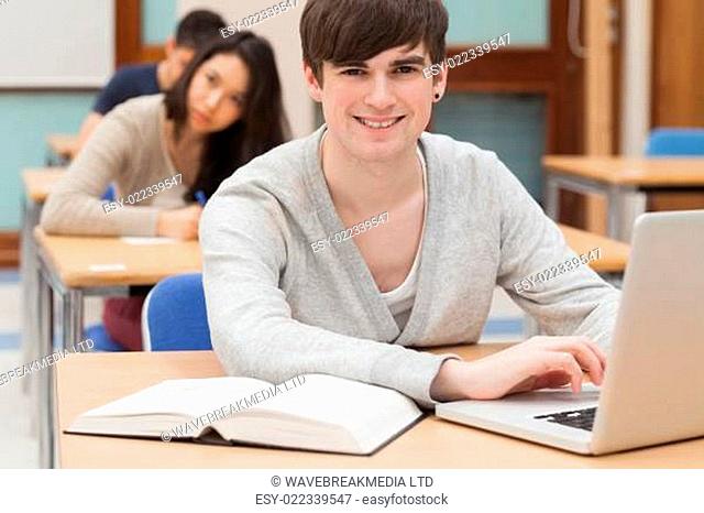 Student sitting at the classroom with laptop while smiling