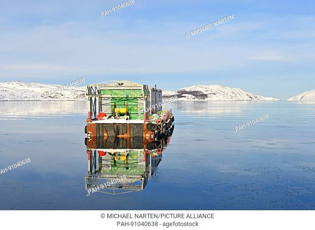 A swimming working platform on the glassy water of the fjord in front of the norwegian town Kirkenes, 8 March 2017 | usage worldwide