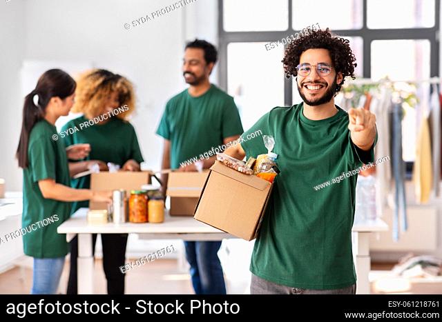 male volunteer with food in box pointing to camera