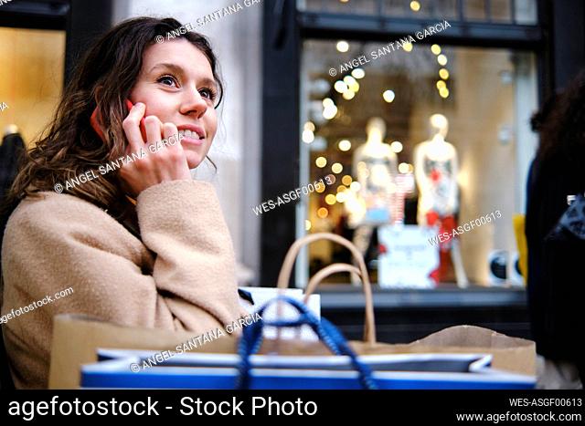 Woman looking away while talking on smart phone by store