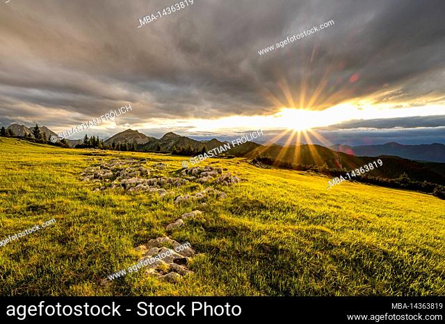 Sunset with cloud atmosphere at Vorderskopf in Karwendel near Hinterriss, in the Alps of Austria with a lush green meadow