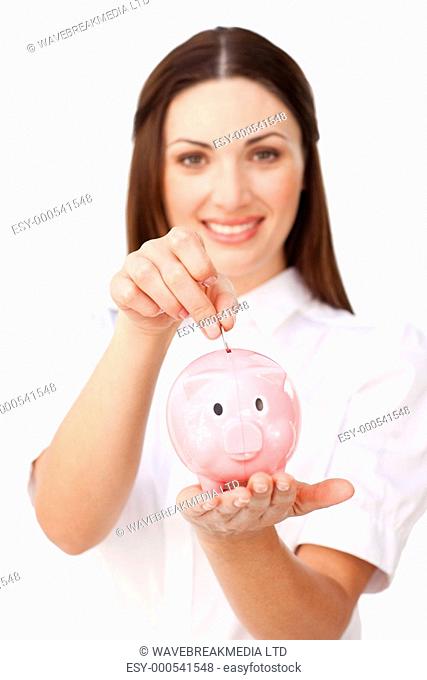 Young brunette businesswoman saving money in a piggybank against a white background