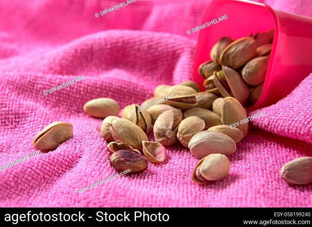 Pistachios in container on pink background
