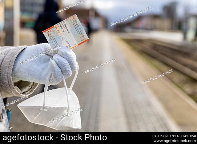 01 February 2023, Brandenburg, Cottbus: A woman holds an FFP-2 mask and a multi-ride ticket for the Cottbus public transport system in her hand
