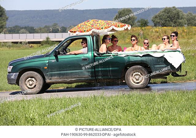dpatop - 30 June 2019, Baden-Wuerttemberg, Unlingen: ""Pool on Tour"": Six young women laid foil on the loading area of a pick-up van