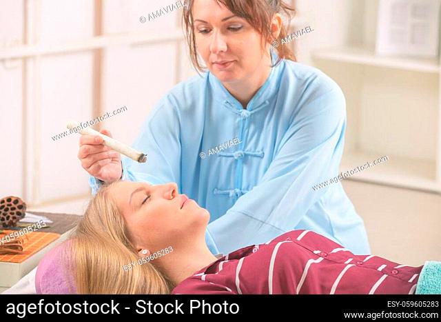 Alternative medicine therapist doing moxa treatment on her client
