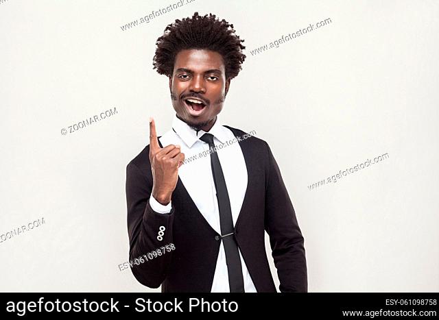 Happiness afro man looking at camera with idea finger. Studio shot, gray background