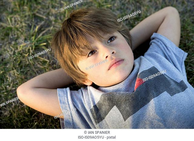 Portrait of boy lying on park grass gazing up