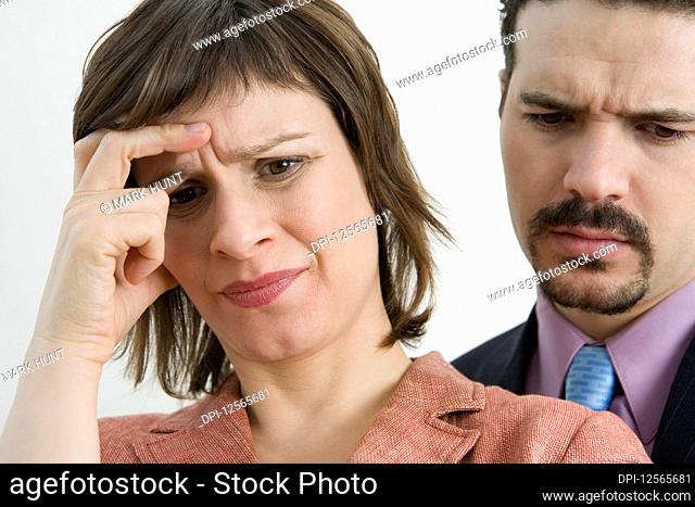 Close-up of a businesswoman suffering from a headache with a businessman behind her