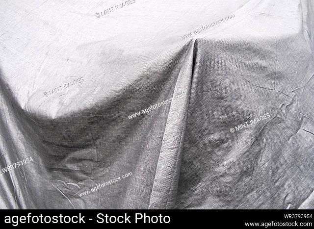 Black and white image, folds of tarpaulin draped across objects