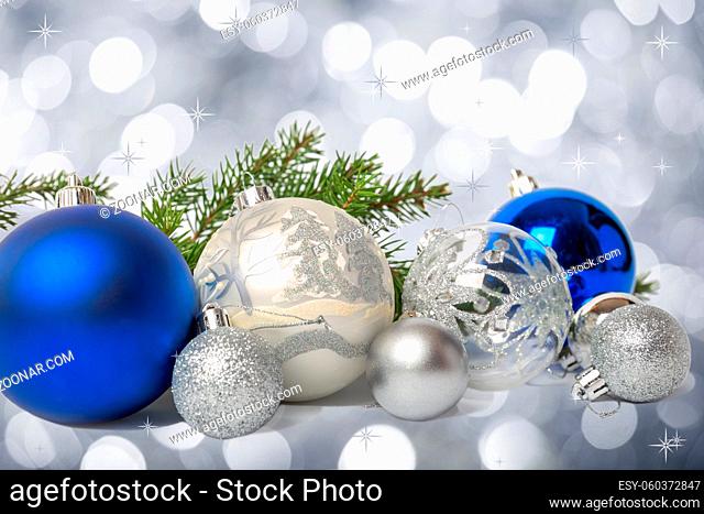 Group of blue and silver Christmas balls and fir branch on silver bokeh background