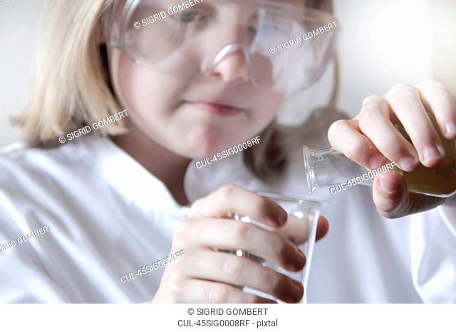 Girl pouring liquid into beakers