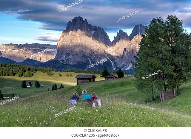 Mountaineers on the Alpe di Siusi admire the alpenglow. In the background the Sella, Sassolungo/Langkofel and Sassopiatto/Plattkofel, Alpe di Siusi, Dolomites