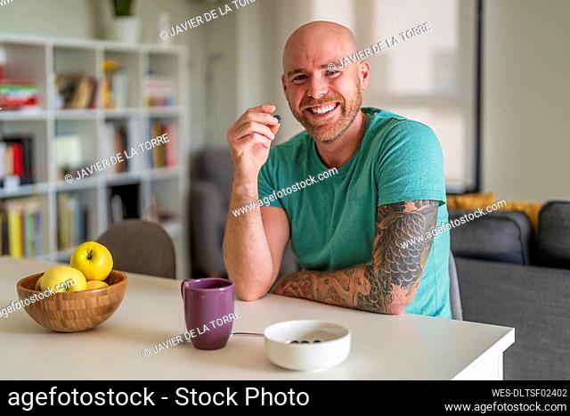 Smiling man having fruit at home