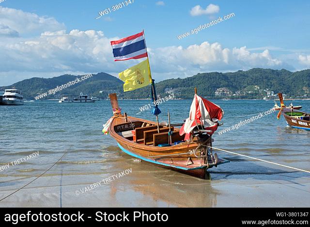 Phuket, Thailand Traditional longtail boat with national flag on the shore of Patong beach at Andaman sea, Phuket island in Thailand