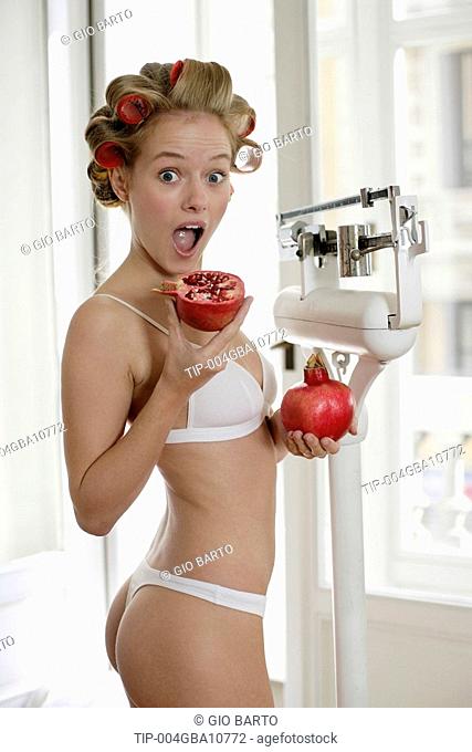 Woman standing on scales holding pomegranates